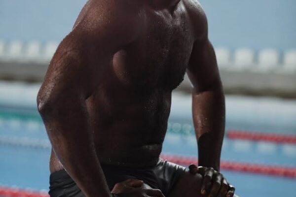A Black man as a swimmer at the pool side with goggles on his head