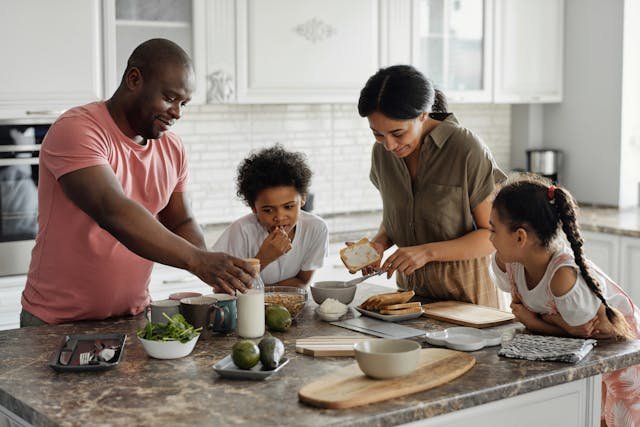 A family consisting of 2 children and Mum & Dad In the Kitchen sampling food