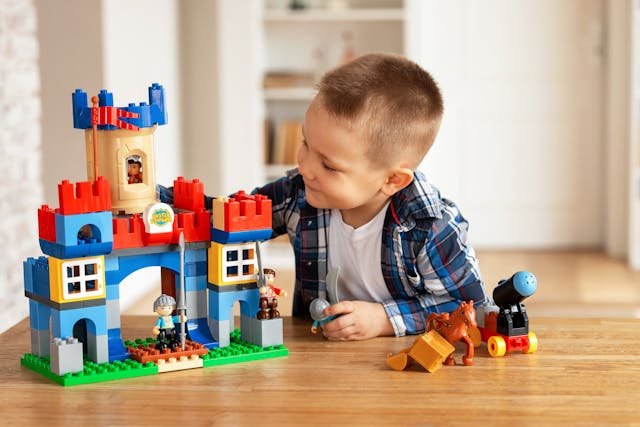 A young boy playing with lego building a castle