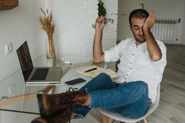 Burnout Isn’t a Badge of Honour A man sitting at his home desk looking tired and rubbing his eyes