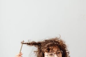 I woman staring outward twirling her hair with a pencil creating a mindless knot