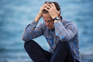 A Man holding his head deep in thought and looking anxious