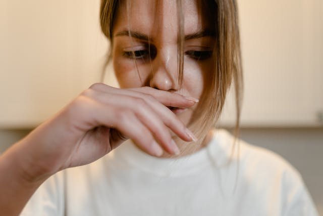 A woman holdeing her index finger to her nose trying to cover up a smell 