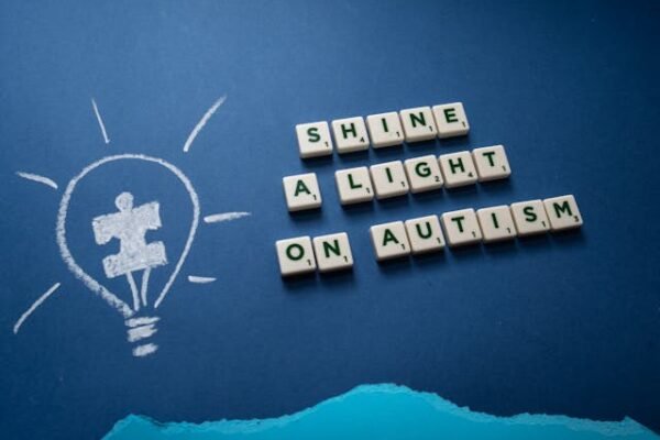 An Image of A slogan of Shine a light on autism spelled on scrabble tiles with a light bulb drawing