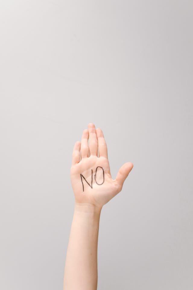 A person's hand in the air with the word No written on their palm