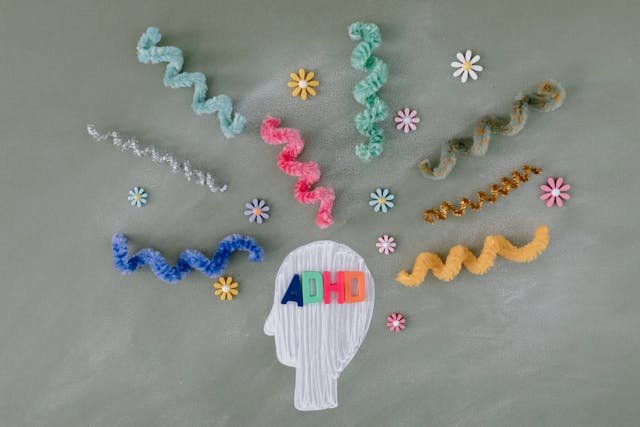 An image of a head with the letters ADHD in different colours on it and several pipecleaners surrounding it for decoration 