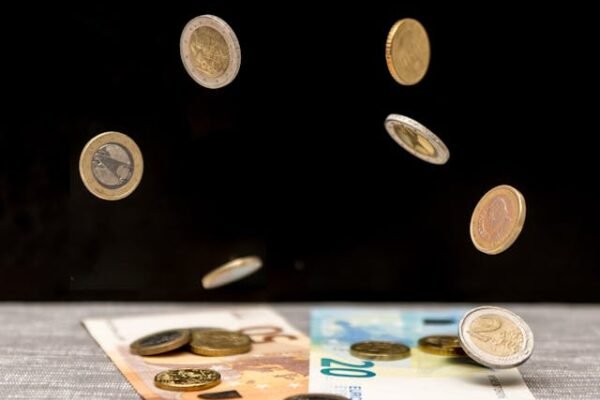 Image of free falling euro coins landing on euro notes on a black background