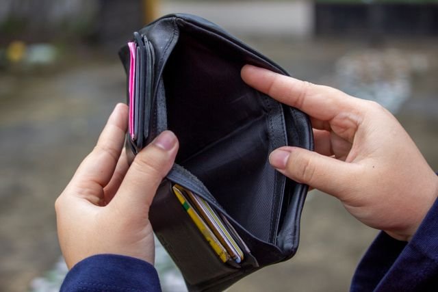 A person looking through their wallet and its empty 