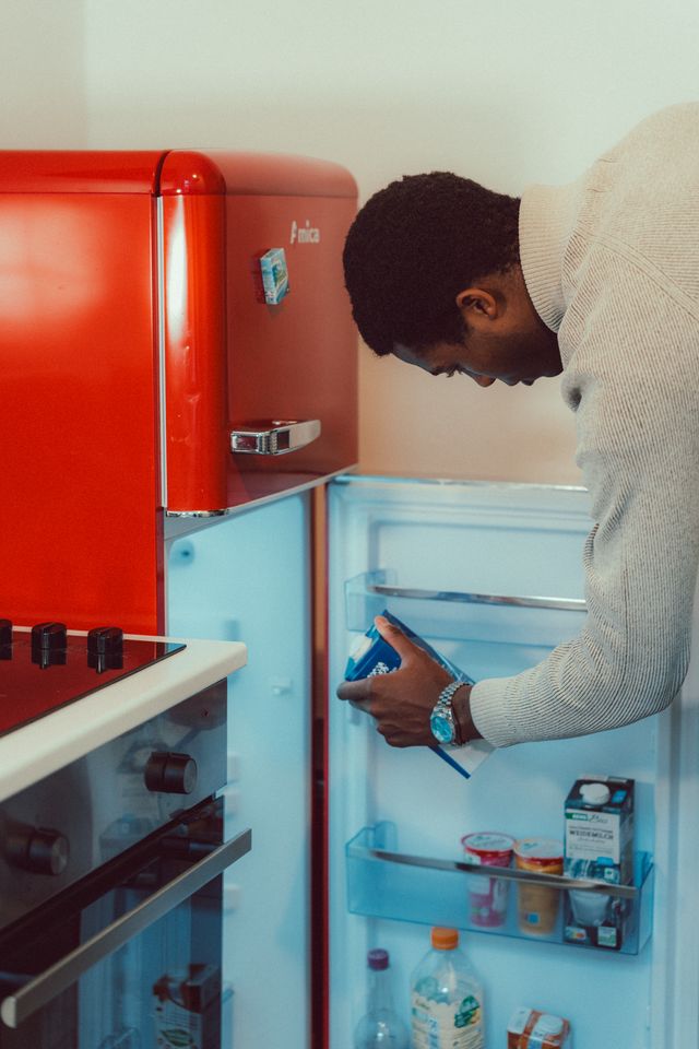 A man putting a carton of milk in the fridge
