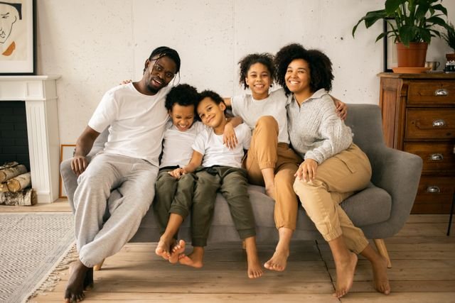 Smiling family on a sofa consisting of Mum, Dad & 3 kids