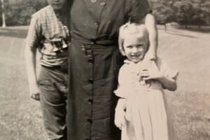 A black & White image of an older lady hugging a child with each arm