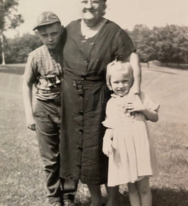 A black & White image of an older lady hugging a child with each arm