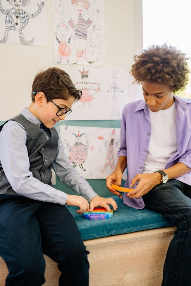 Image of 2 tween boys in a classroom playing with a popping gadget