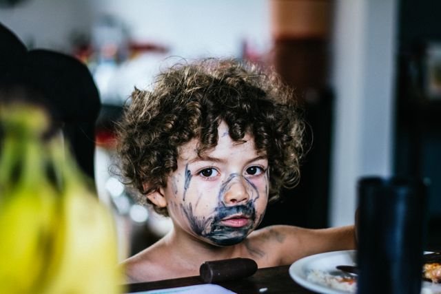 A young boy with paint drawn all over his face